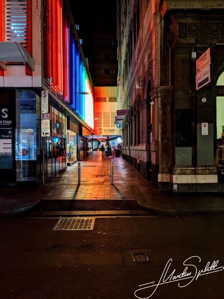 Eine Seitenstrasse, die tagsüber grau und unscheinbar ist, erstrahlt in Regenbogenfarben in der Nacht